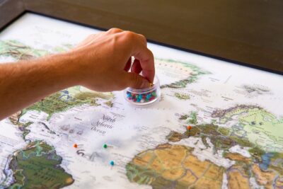 Épingles colorées plantées sur une carte du monde pour préparer un voyage